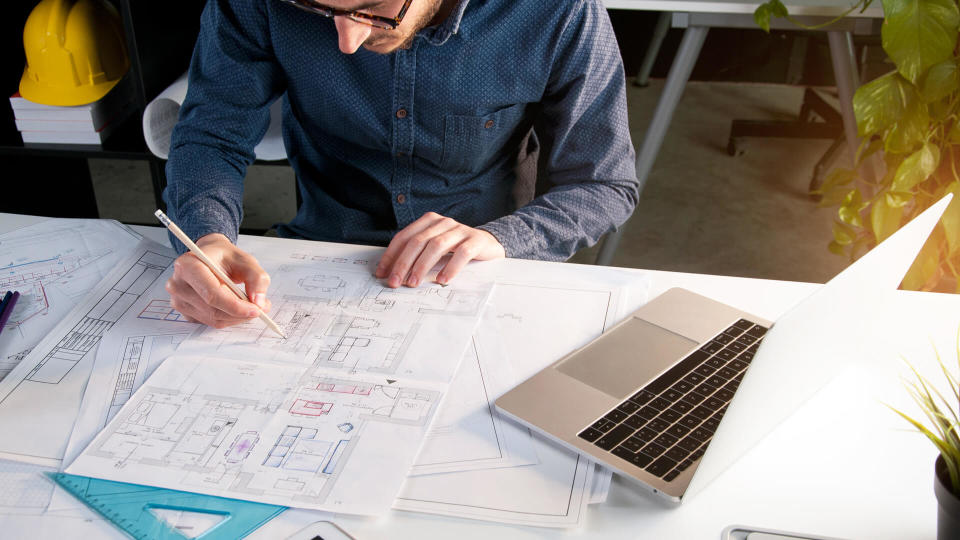 Architect working in office with house project on desk.