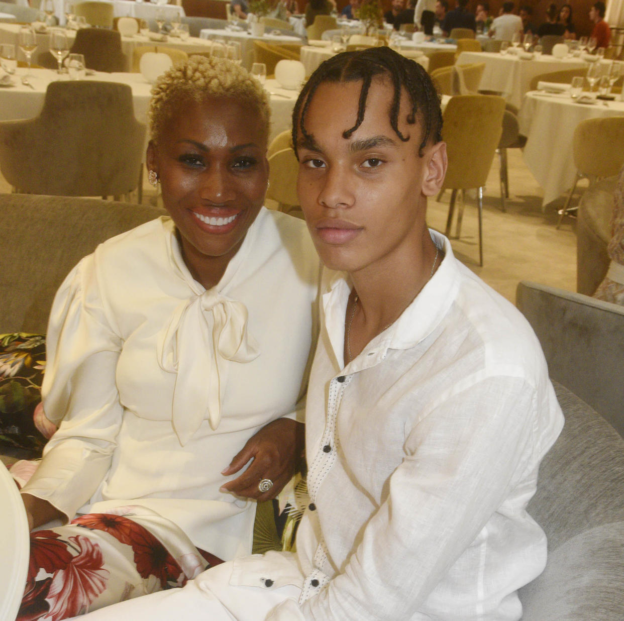 Nicole Coste and her son Alexandre in casual white outfits in a ballroom. (Foc Kan / FilmMagic)
