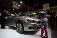 A child poses for photos near a Volvo S60L at the China Auto in Beijing, China, Sunday, April 20, 2014. (AP Photo/Ng Han Guan)