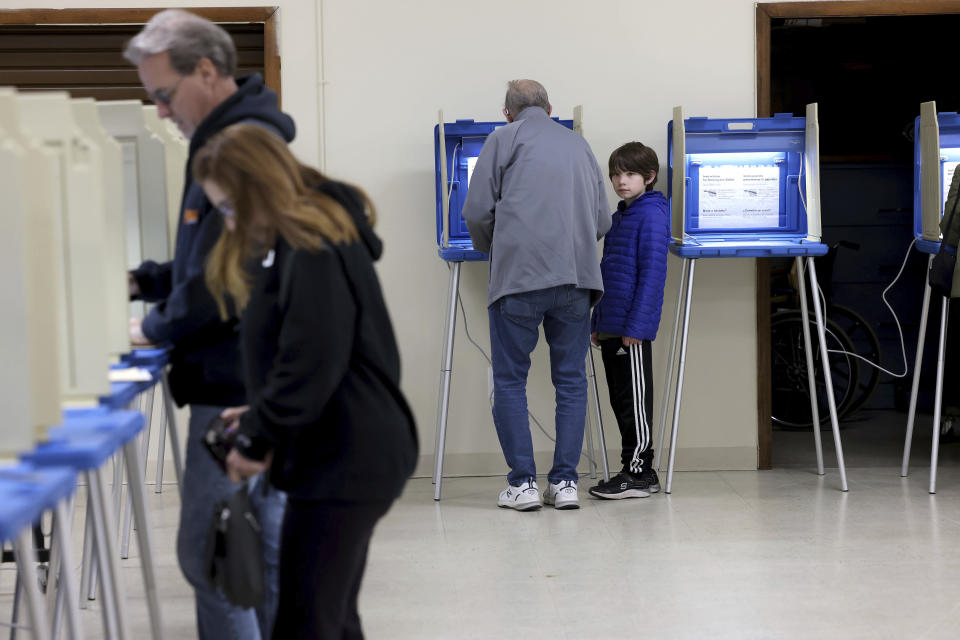 Arthur Crookes, center, fills out his ballot as his grandson, Joseph Godek, 9, right, watches at a polling station in Cumberland, R.I. during the state's primary election, Tuesday, April 2, 2024. Rhode Island is one of four states holding primary elections on Tuesday. (AP Photo/Mark Stockwell)