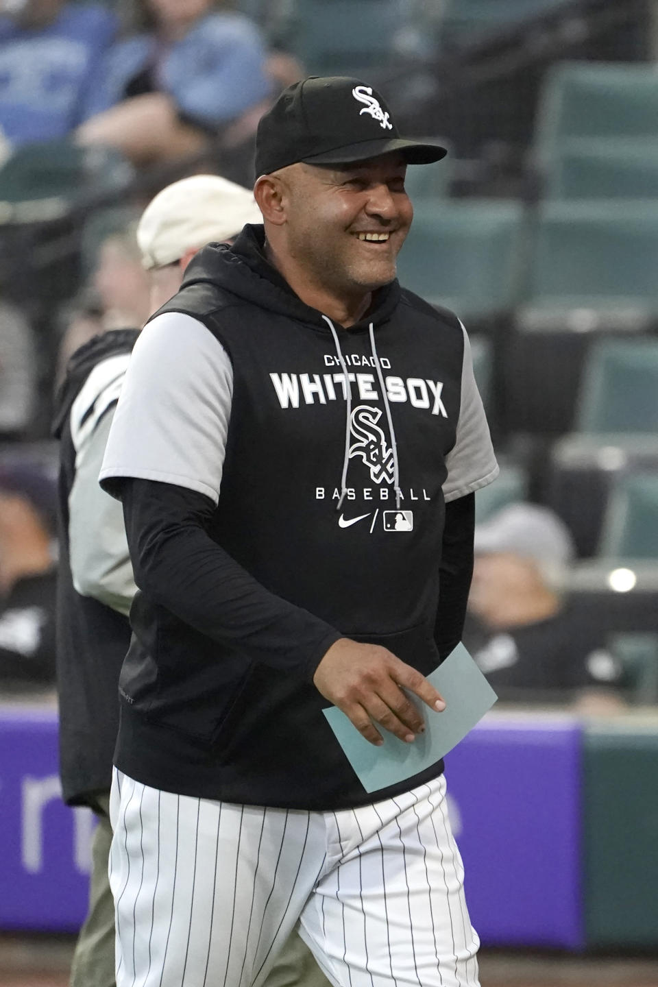 Chicago White Sox bench coach Miguel Cairo smiles as he returns to the dugout with the lineup card after the White Sox announced that Cairo would manage the team in the absence of manager Tony La Russa, who will undergo further medical testing at the direction of his doctors with an undisclosed illness, before the team's baseball game agains the Kansas City Royals on Tuesday, Aug. 30, 2022, in Chicago. (AP Photo/Charles Rex Arbogast)