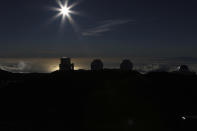 The sun sets behind telescope at the summit of Hawaii's Mauna Kea, Sunday, July 14, 2019. Hundreds of demonstrators are gathered at the base of Hawaii's tallest mountain to protest the construction of a giant telescope on land that some Native Hawaiians consider sacred. State and local officials will try to close the road to the summit of Mauna Kea Monday morning to allow trucks carrying construction equipment to make their way to the top. Officials say anyone breaking the law will be prosecuted. Protestors have blocked the roadway during previous attempts to begin construction and have been arrested. (AP Photo/Caleb Jones)