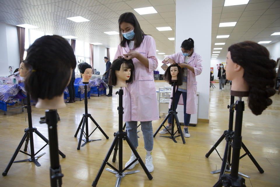 Students braid wigs during a class at the Peyzawat Training School in Peyzawat County in China's far west Xinjiang region, as seen during a state-organized tour for foreign media on April 19, 2021. Four years after Beijing's brutal crackdown on largely Muslim minorities native to Xinjiang, Chinese authorities are dialing back the region's high-tech police state and stepping up tourism. But even as a sense of normality returns, fear remains, hidden but pervasive. (AP Photo/Mark Schiefelbein)