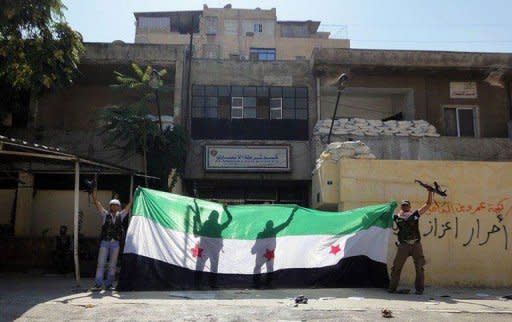 A picture released by the Syrian opposition's Shaam News Network shows rebels celebrating with a pre-Baath Syrian flag after taking over a police station in Aleppo. UN chief Ban Ki-moon told world powers they must overcome their rivalries to put an end to the "proxy war" in Syria, as deadly fighting raged in Damascus and the country's second city Aleppo