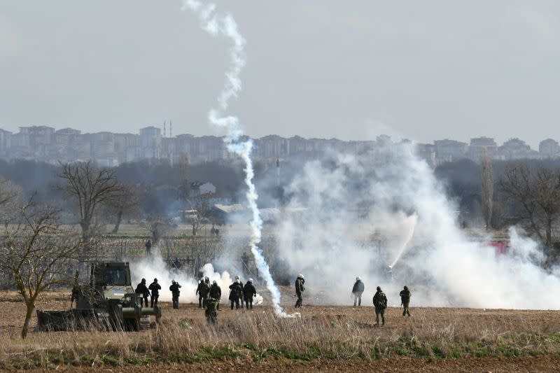 Greek riot police officers stand guard as tear gas is being fired near Turkey's Pazarkule border crossing, in Kastanies