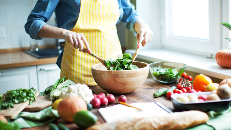 Person in an apron tossing a salad