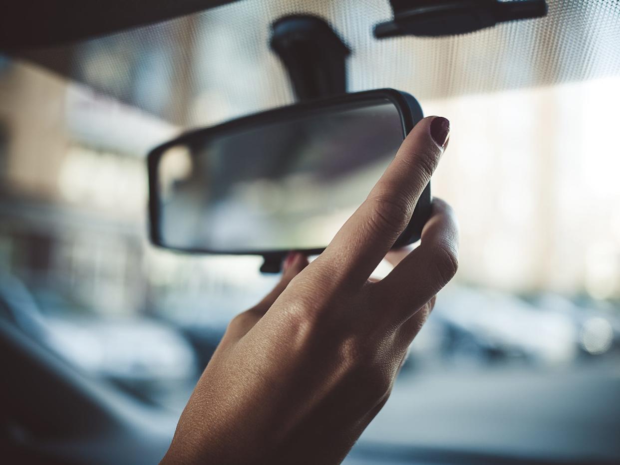 Person's hand adjusting rearview mirror.