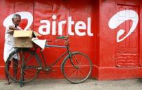 A man packs goods on the back of his bicycle as he stands next to the wall of a grocery shop painted with an advertisement for Bharti Airtel in the southern Indian city of Kochi May 5, 2011. REUTERS/Sivaram V/File Photo