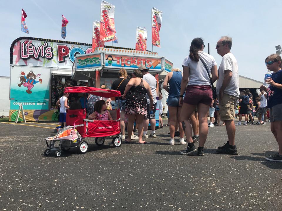 Fair-goers stand in line for tickets to rides on the midway at the St. Joseph County 4-H Fair on Sunday, July 4, 2021.