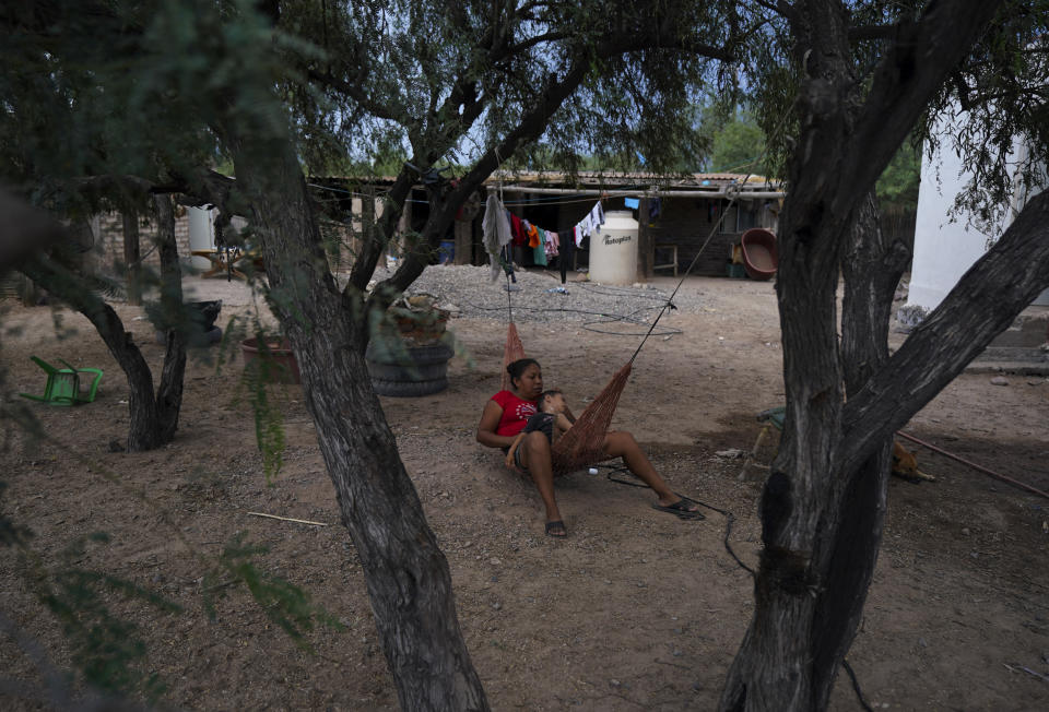 A Yaqui Indigenous woman and child rest in a hammock in their yard in the hometown of slain water-defense leader Tomás Rojo, in Potam, Mexico Tuesday, Sept. 27, 2022. The Yaquis are the legal owners of at least half the water in the river basin that bears their name, but they have seen their share of the water redirected to feed burgeoning industries and schemes to plant vineyards and avocados in the desert. (AP Photo/Fernando Llano)