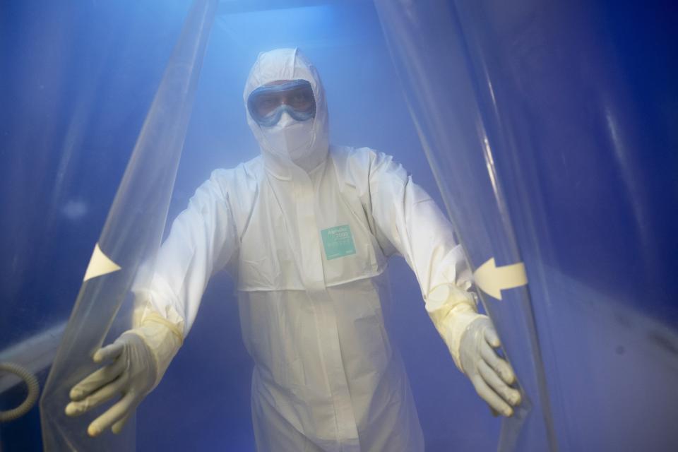 In this photo taken on Saturday, May 16, 2020, Dr. Osman Osmanov walks through a disinfectant sluice after his shift at an intensive care unit of the Filatov City Clinical Hospital in Moscow, Russia. Moscow accounts for about half of all of Russia's coronavirus cases, a deluge that strains the city's hospitals and has forced Osmanov to to work every day for the past two months, sometimes for 24 hours in a row. (AP Photo/Pavel Golovkin)