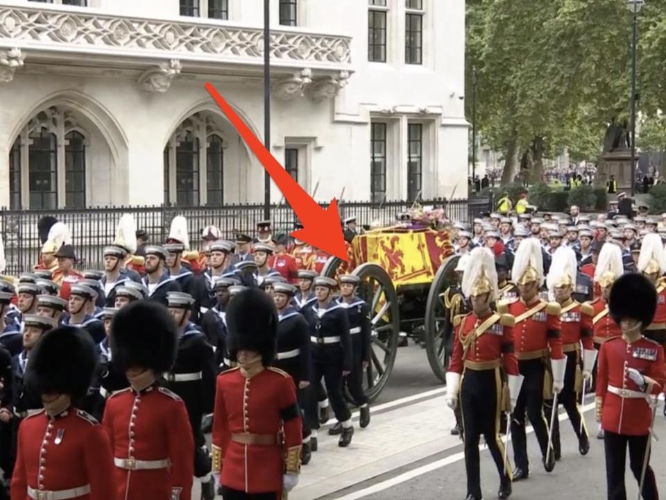 arrow pointing to carriage carrying queen's coffin in crowd of sailors and guards