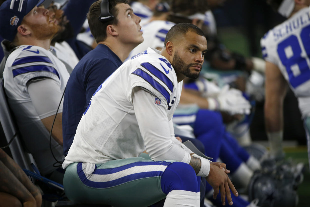 Dallas Cowboys quarterback Dak Prescott (4) and offensive coordinator Kellen Moore, rear, sit on the bench late in the second half of an NFL football game against the Buffalo Bills in Arlington, Texas, Thursday, Nov. 28, 2019. (AP Photo/Ron Jenkins)