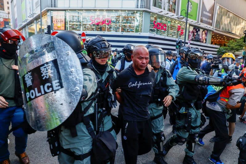 Riot policemen detain a man in Causeway Bay district before a protest march in Hong Kong