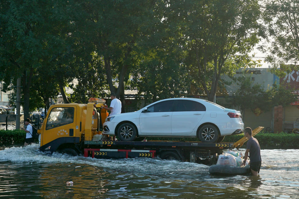 A tow truck drives along a flooded street in Xinxiang in central China's Henan Province, Monday, July 26, 2021. Forecasters Monday said more heavy rain is expected in central China's flood-ravaged Henan province, where the death toll continues to rise after flash floods last week that killed dozens of people. (AP Photo/Dake Kang)