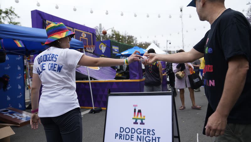 A Los Angeles Dodgers Pride promoter gives a ball to a participant at the WeHo Pride Parade in West Hollywood, Calif., on Sunday, June 4, 2023.