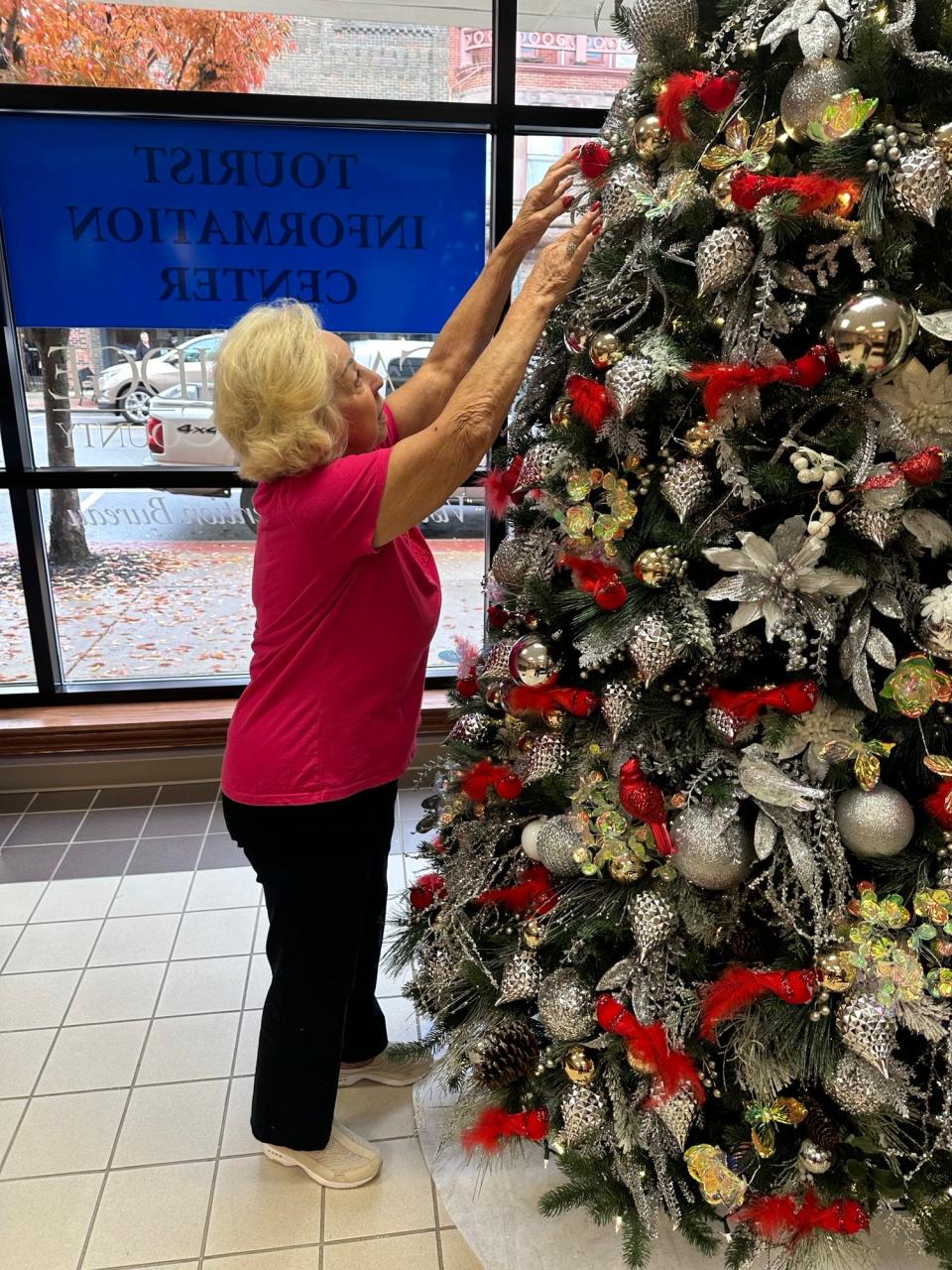 Bonnie Perkins decorates the Christmas tree in the lobby of the Cambridge/Guernsey County Visitors Bureau.