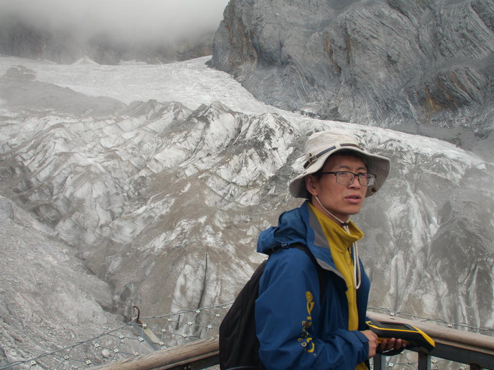 This Sept. 22, 2018 photo shows geologist Chen Yanjun overlooking the Baishui Glacier No.1 on the Jade Dragon Snow Mountain in the southern province of Yunnan in China. Scientists say the glacier is one of the fastest melting glaciers in the world due to climate change and its relative proximity to the Equator. It has lost 60 percent of its mass and shrunk 250 meters since 1982. (AP Photo/Sam McNeil)