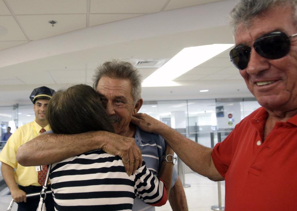 In this Sept. 11, 2013, photo, Benito Perez, center, is greeted by his friends Rogelia Ventura and Luis Ventura, right, at his arrival at Miami International Airport, in Miami. Perez, who had never been on a plane, is one of thousands of Cubans traveling under new laws making travel slightly easier. (AP Photo/Alan Diaz)