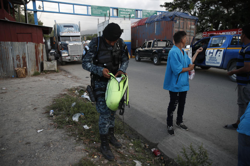 Guatemalan National Police agents check a backpack of a Honduras migrant trying to reach the United States at El Cinchado, Guatemala, in the border with Honduras, Wednesday, Jan. 15, 2020. Hundreds of mainly Honduran migrants started walking and hitching rides Wednesday from the city of San Pedro Sula and crossed the Guatemala border in a bid to form the kind of migrant caravan that reached the U.S. border in 2018. (AP Photo/Moises Castillo)