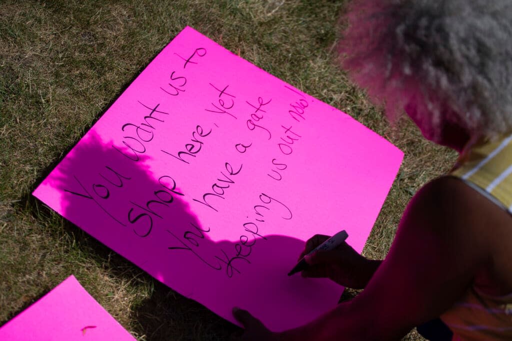 Cariol Horne, 54, makes a sign to hold as she stands outside the fenced-off parking lot outside Tops Friendly Market during a remembrance ceremony on Thursday, July 14, 2022, in Buffalo, N.Y. (AP Photo/Joshua Bessex)