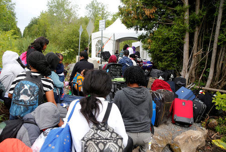 FILE PHOTO: A line of asylum seekers who identified themselves as from Haiti wait to enter into Canada from Roxham Road in Champlain, New York, U.S., August 7, 2017. REUTERS/Christinne Muschi/File Photo