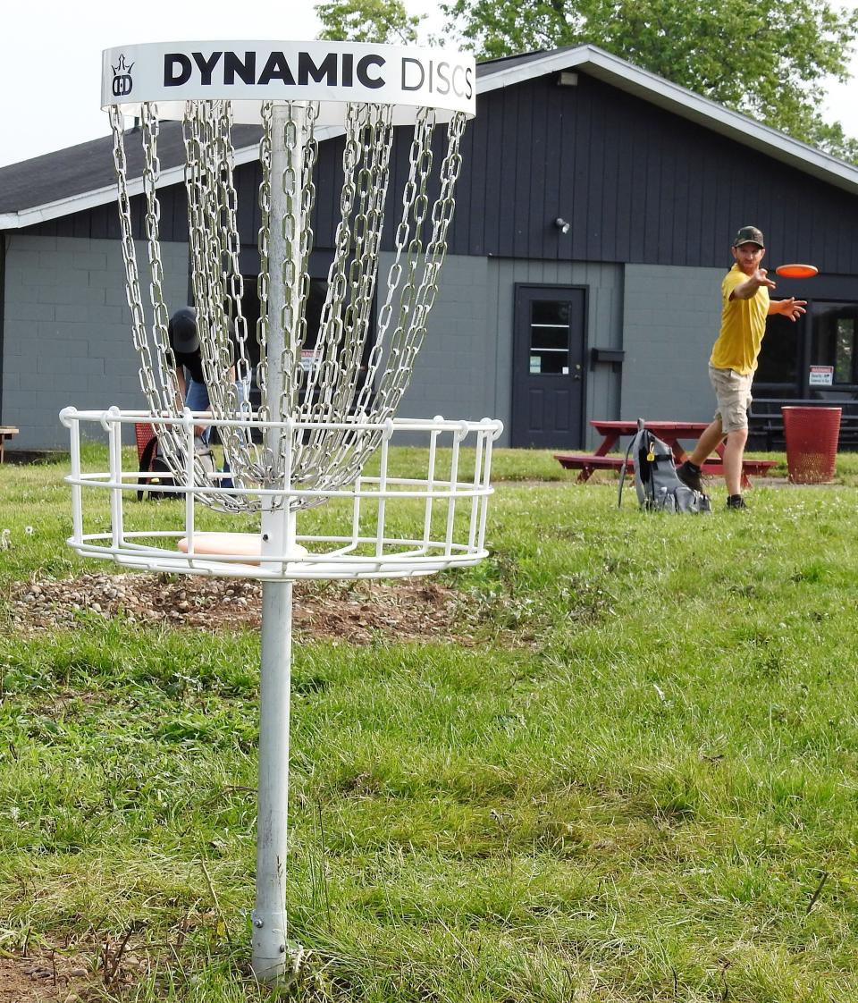 Marion Troyer throws a disc at a basket at the new Eagle Ridge Disc Golf Course, near Lake Park. The free park was created via volunteer efforts.