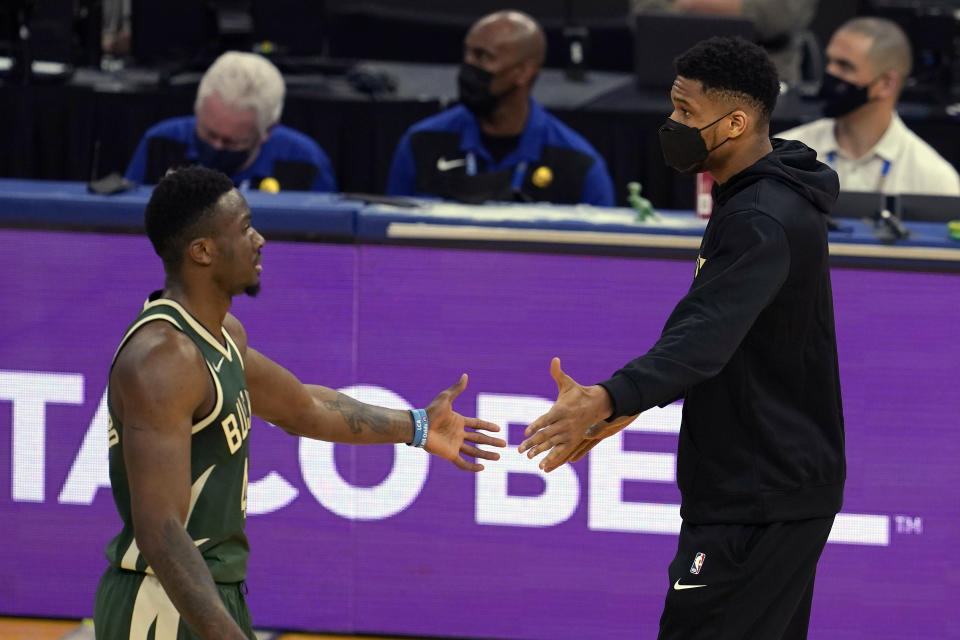 Injured Milwaukee Bucks forward Giannis Antetokounmpo, right, greets forward Thanasis Antetokounmpo during the first half of an NBA basketball game against the Golden State Warriors in San Francisco, Tuesday, April 6, 2021. (AP Photo/Jeff Chiu)