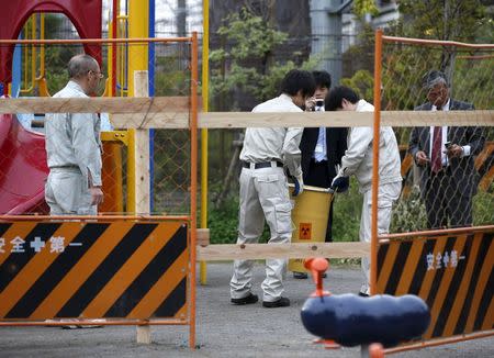 Workers of Tokyo's Toshima ward office carry away a container holding a fragment of an unknown object after it was dug up from the ground near playground equipment at a park in Toshima ward, Tokyo April 24, 2015. REUTERS/Toru Hanai