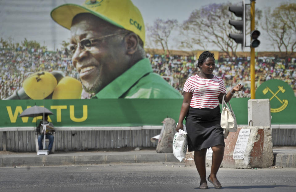 FILE - In this Oct. 26, 2015 file photo, a Tanzanian woman walks past a billboard for the ruling party's then presidential candidate John Magufuli, in Dar es Salaam, Tanzania. President John Magufuli of Tanzania, a prominent COVID-19 skeptic whose populist rule often cast his country in a harsh international spotlight, has died aged 61 of heart failure, it was announced Wednesday, March 17, 2021 by Vice President Samia Suluhu. (AP Photo/Khalfan Said, File)