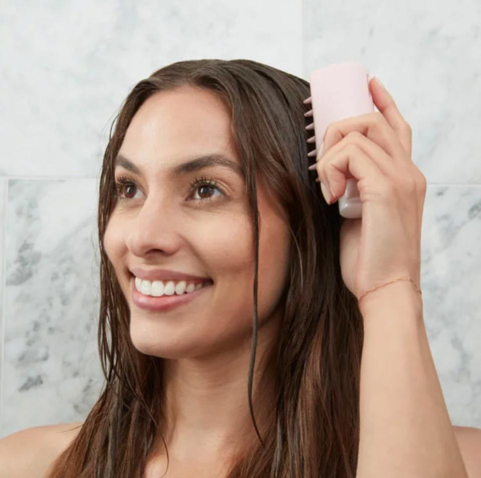 a model using the pink textured bottle as a scalp scrubber