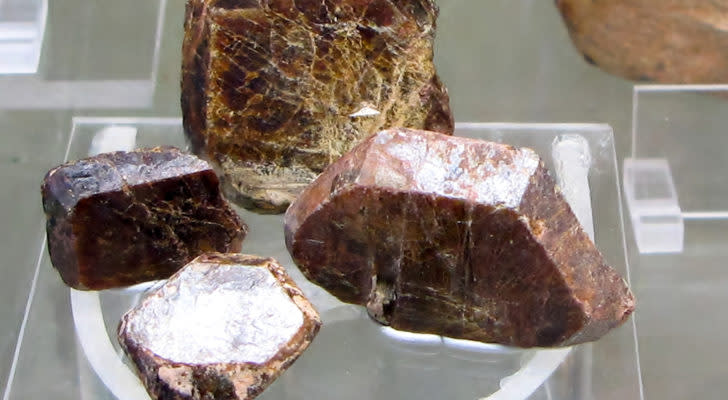 Several crystals of the rare earth metal gadolinium are on display on a clear surface.