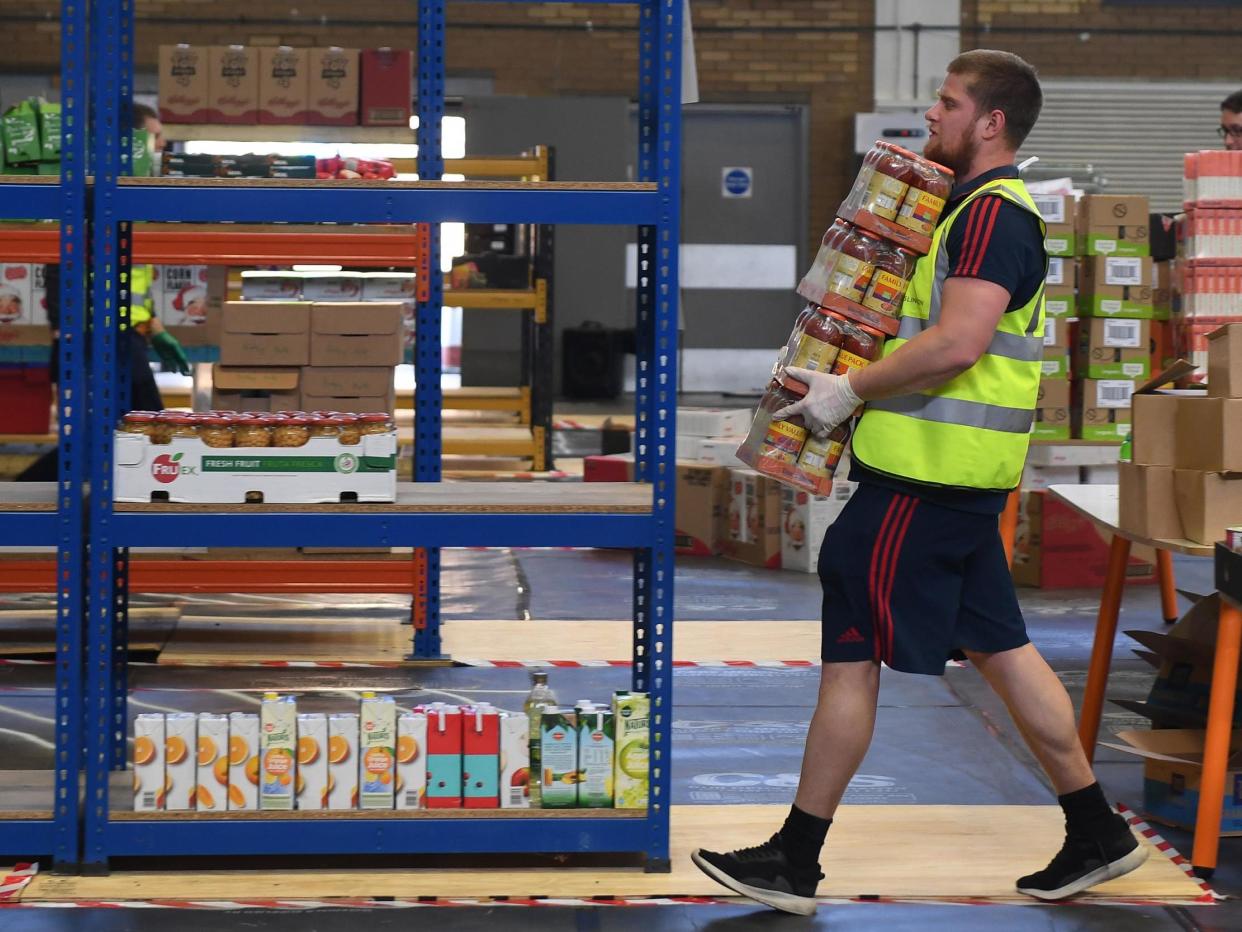 People collect food packages as the Arsenal Foundation And HIS Church prepare to deliver food parcels for local residents at the Emirates stadium: Arsenal FC via Getty Images