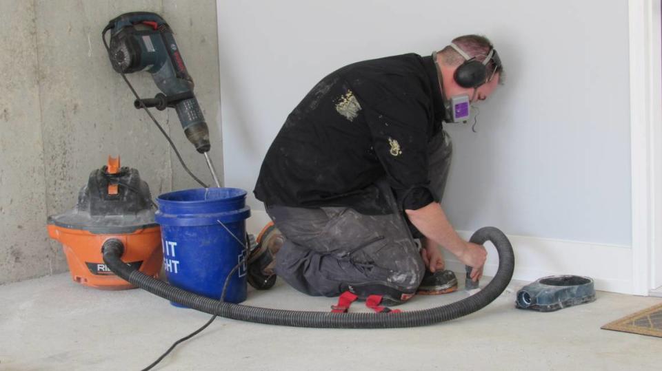 Jacob Kincaid, a mitigation/measurement specialist with Alpha Radon Remediation in Lexington, Ky., removed gravel from a hole he drilled in the floor of a basement in Stanford, Ky., on May 24, 2023 as part of a system to remove radon from the home.