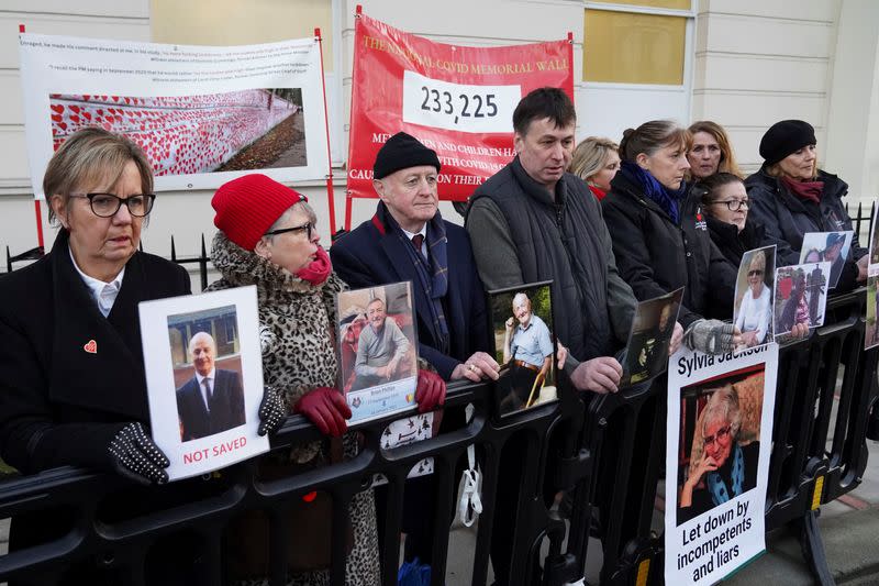 Manifestantes sostienen fotos mientras esperan fuera de la investigación del COVID-19 en el Reino Unido, donde el ex primer ministro británico Boris Johnson está dando testimonio, en Londres