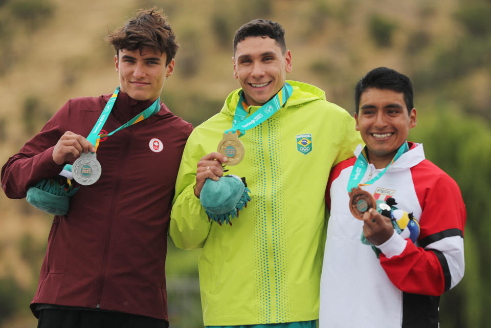 El medallista de oro de Brasil, Guilherme Marcello Mapelli, celebra en el podio con su medalla después de ganar la final masculina de kayak cross K1 junto al medallista de plata, Alex Baldoni, de Canadá, y el medallista de bronce, de Perú. Foto: Reuters
