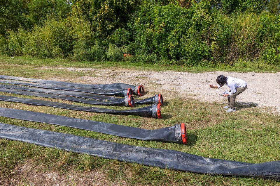 Jefferson Parish President Cynthia Lee Sheng, right, takes photos of the flexible pipeline being installed that will help supply fresh water to Jefferson Parish as salt water slowly moves up the Mississippi River on Wednesday, Oct. 4, 2023, in Marrero, La.