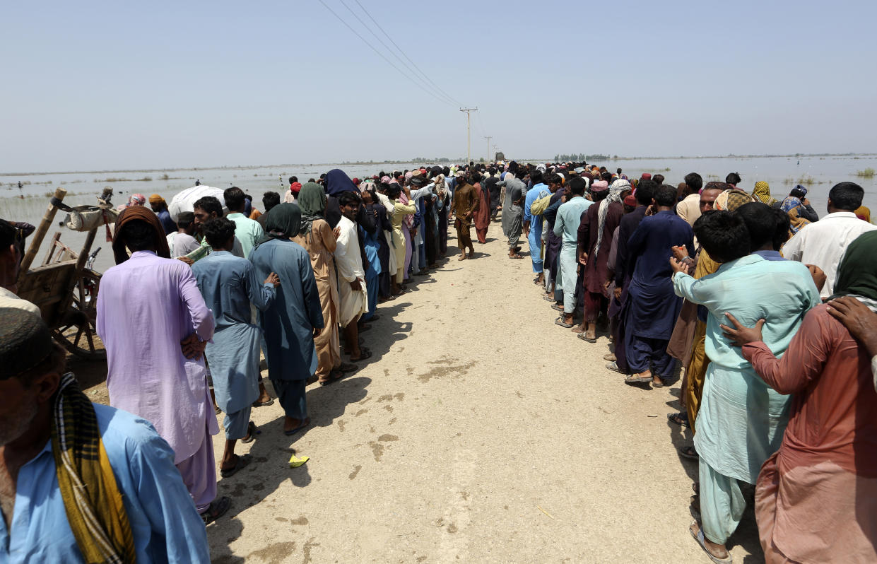 Victims of heavy flooding from monsoon rains wait to receive relief aid from the Pakistani Army in the Qambar Shahdadkot district of Sindh Province, Pakistan, Friday, Sept. 9, 2022. U.N. Secretary-General Antonio Guterres appealed to the world for help for cash-strapped Pakistan after arriving in the country Friday to see the climate-induced devastation from months of deadly record floods. (AP Photo/Fareed Khan)