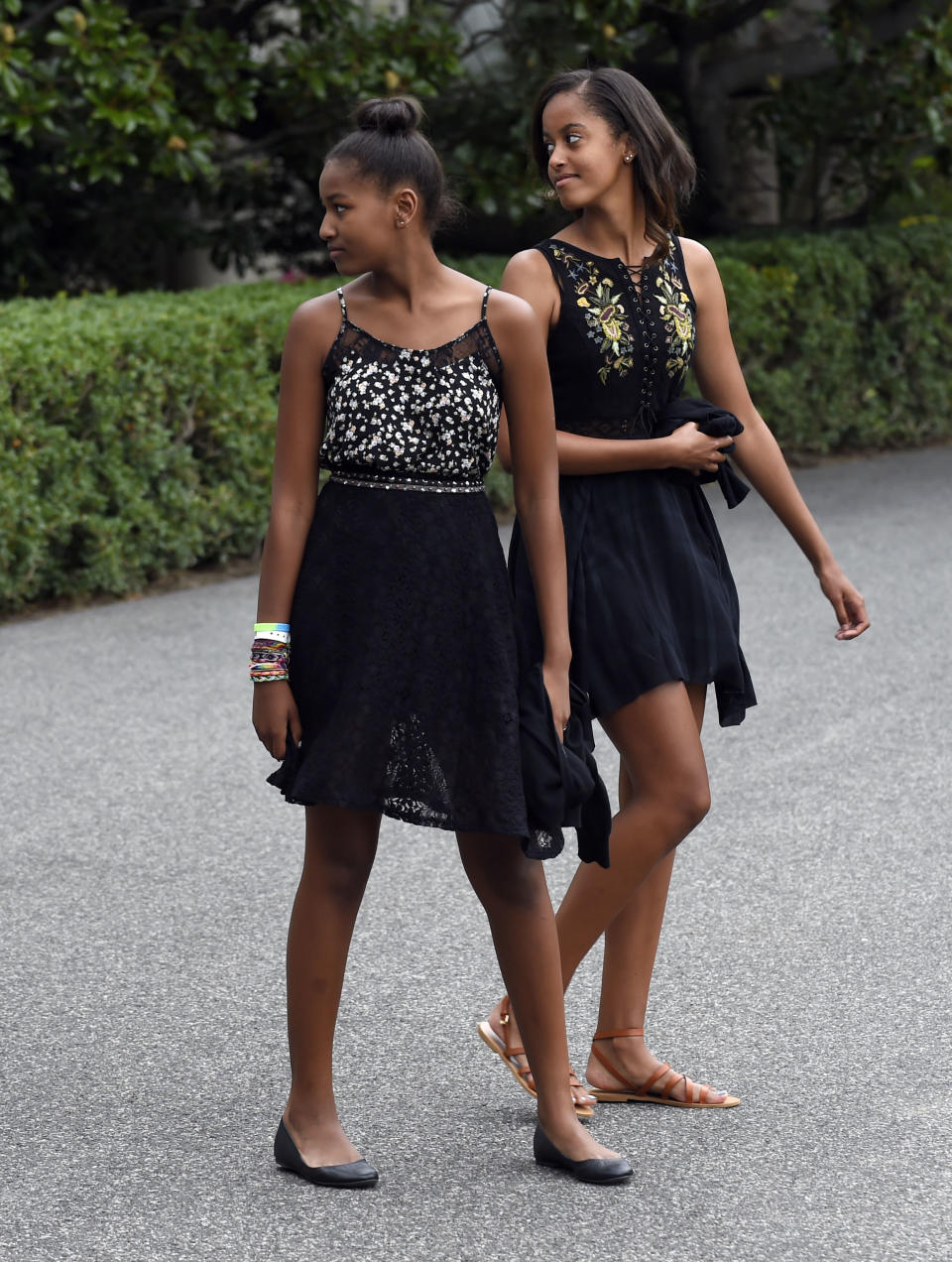 First daughters Sasha Obama, left, and Malia Obama look back for their parents as they walk out of the White House in Washington, Saturday, Aug. 30, 2014, and head to Marine One.