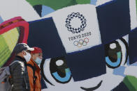 People walk by posters to promote the Tokyo 2020 Olympics planned to start in the summer of 2021, in Tokyo, Tuesday, Jan. 19, 2021. Tokyo organizers have no public program planned to mark the milestone. There is too much uncertainty for that right now. Tokyo and other parts of Japan are under an emergency order because of surging coronavirus cases. (AP Photo/Koji Sasahara)