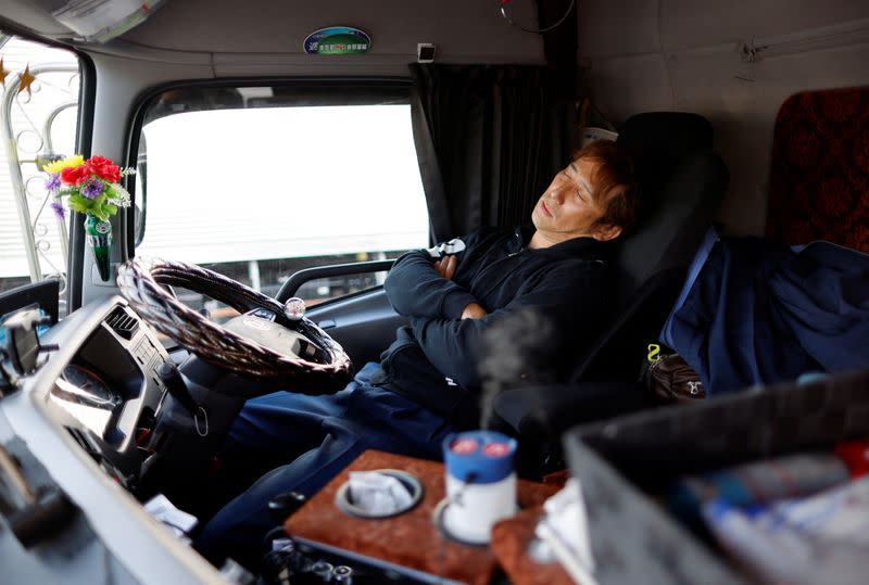 A truck driver Yuichi Tomita takes a break inside his truck during his delivery work at a parking area along the highway in Chiba