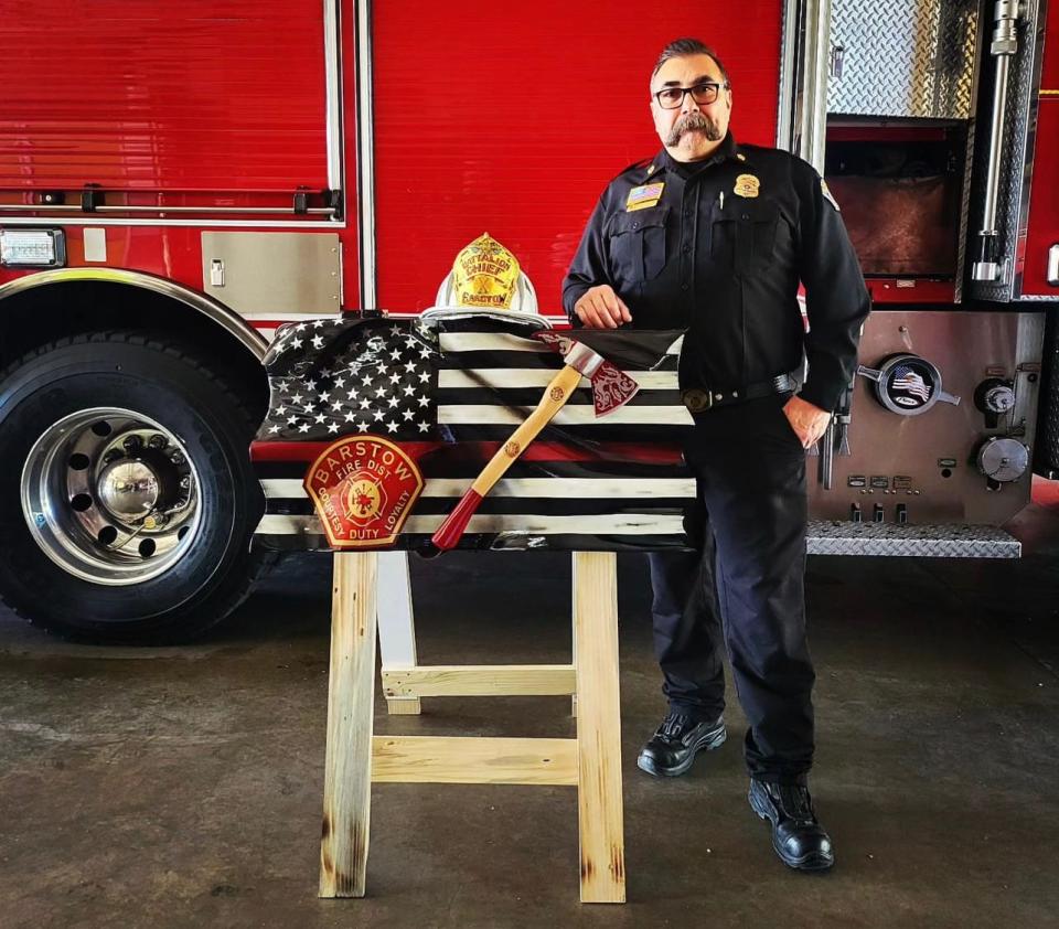 Barstow Fire Chief Nick DiNapoli with a handcrafted patriotic flag designed and gifted to the fire department by wood sculptor Rob Rivera of Apple Valley.