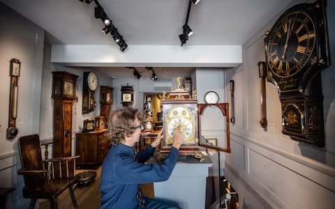 Antique clock seller Howard Walwyn goes through his shop in Kensington, London, changing the time on all the clocks - Credit: John Nguyen/JNVisuals