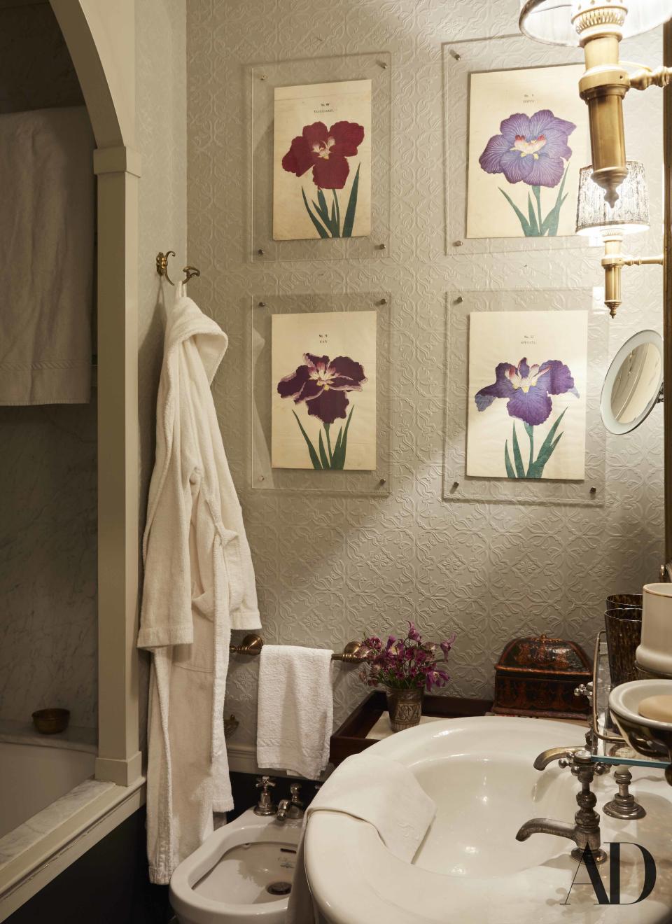 Four vintage Japanese watercolor engravings are displayed on the bathroom's embossed wallpaper; sconces by Studio Peregalli.