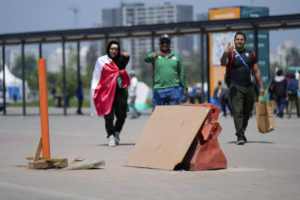 People arrive to the National Stadium compound of the Pan American Games in Santiago, Chile, Monday, Oct. 23, 2023. Near the stadium’s main entrance, dozens of empty boxes, crates and pieces of wood lay untouched between Friday, day of the Opening Ceremony, and Saturday. (AP Photo/Silvia Izquierdo)