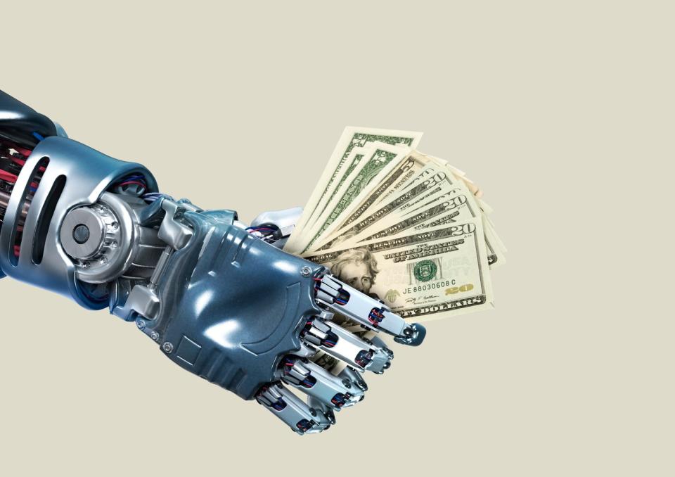 A robotic hand holds a stack of twenty-dollar bills.