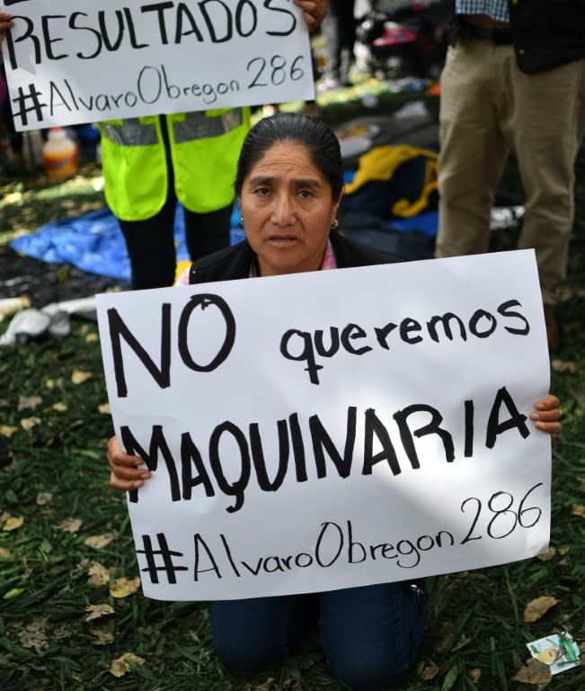 A woman whose relatives are feared buried in a building holds a sign saying "We don't want machinery" in a bid to stave off the use of bulldozers