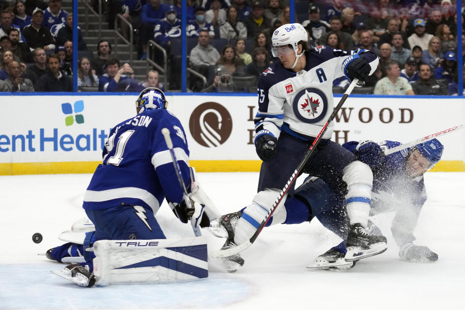 Winnipeg Jets center Mark Scheifele (55) is hit by Tampa Bay Lightning defenseman Mikhail Sergachev (98) as he loses the puck in front of goaltender Jonas Johansson (31) during the first period of an NHL hockey game Wednesday, Nov. 22, 2023, in Tampa, Fla. (AP Photo/Chris O'Meara)