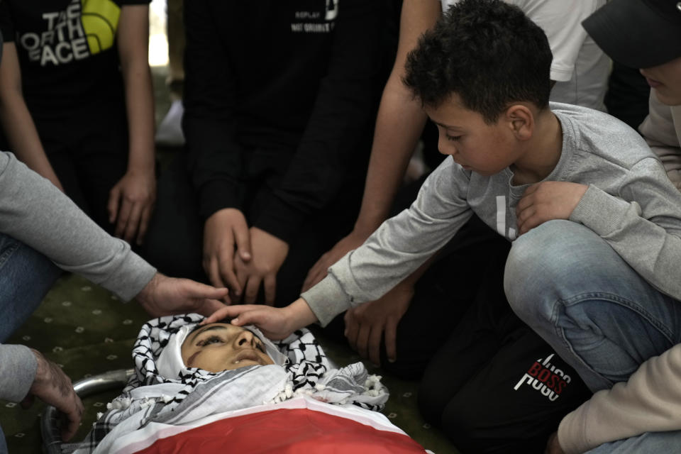 Mourners gather around the body of Mutasim Abu Abed, 13, during his funeral in Qabatiya, near the West Bank city of Jenin, Saturday, March 30, 2024. Dr. Fawaz Hamad, director of Al-Razi Hospital in Jenin, told local station Awda TV that Israeli forces killed a 13-year-old boy in nearby Qabatiya early Saturday. Israel's military said the incident was under review. (AP Photo/Majdi Mohammed)