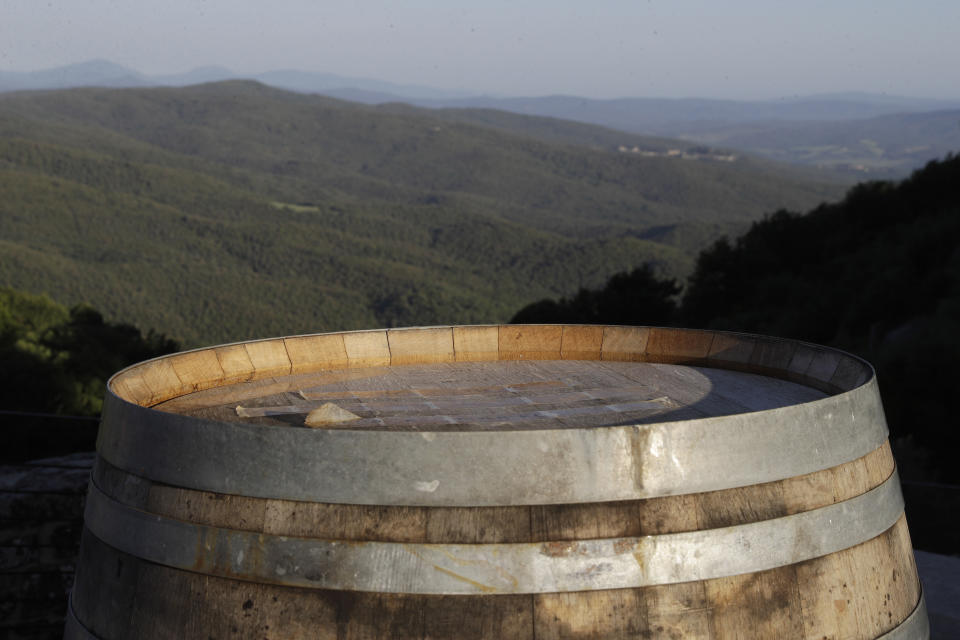 A jar of Brnuello is backdropped by the hills of the Val D' Orcia in Montalcino, Italy, Friday, May 28, 2021. It is a long way, and a risky one. But for this group of migrants at least it was worth the effort. They come from Ghana, Togo, Sierra Leone, Pakistan, Guinea Bissau, among other countries. They all crossed the Sahara desert, then from Libya the perilous Mediterranean Sea until they reached Italian shores, now they find hope working in the vineyards of Tuscany to make the renown Brunello wine. (AP Photo/Gregorio Borgia)